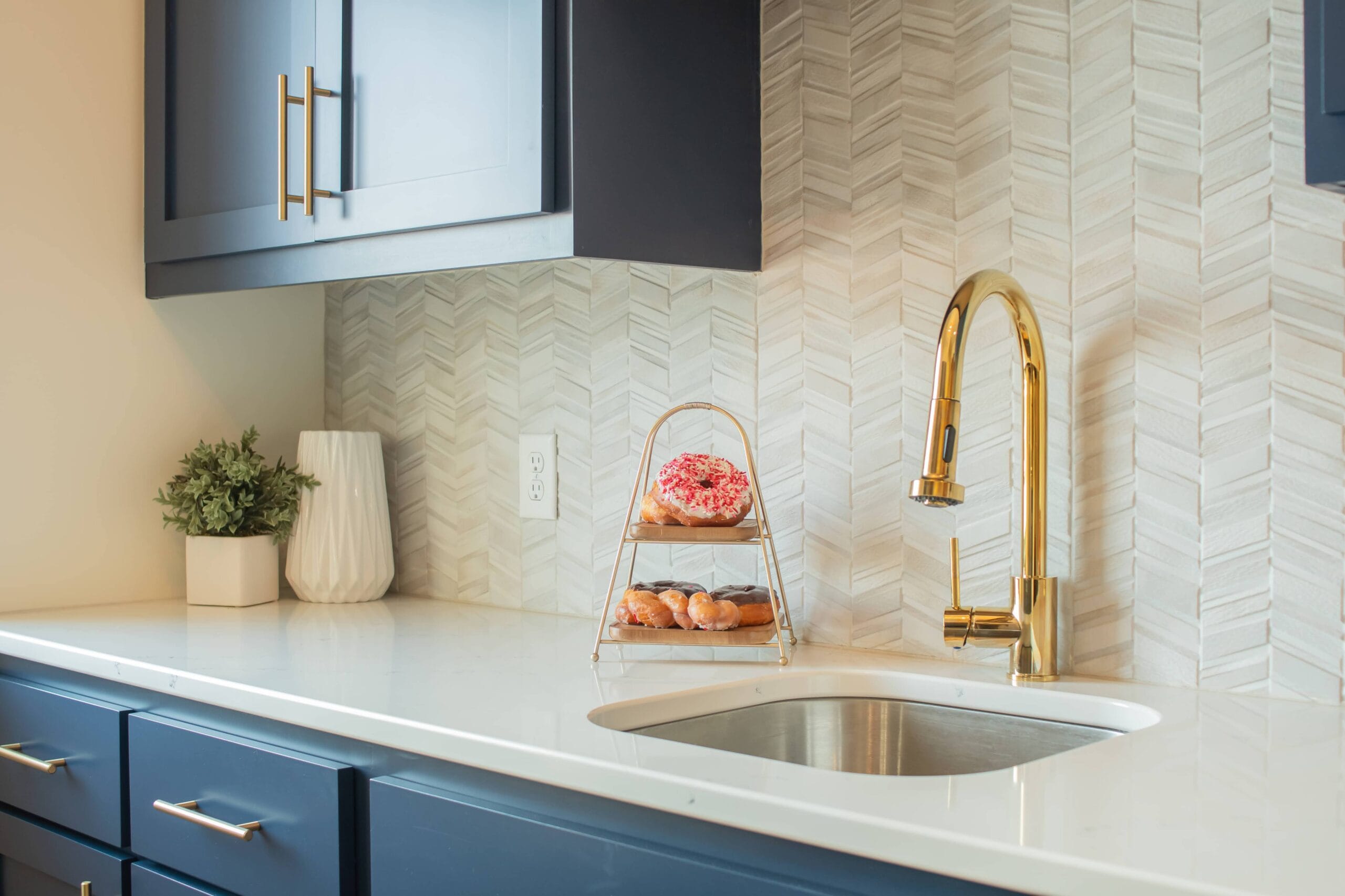 Golden Faucet with blue cabinet and donuts with pink icy and sprinkles