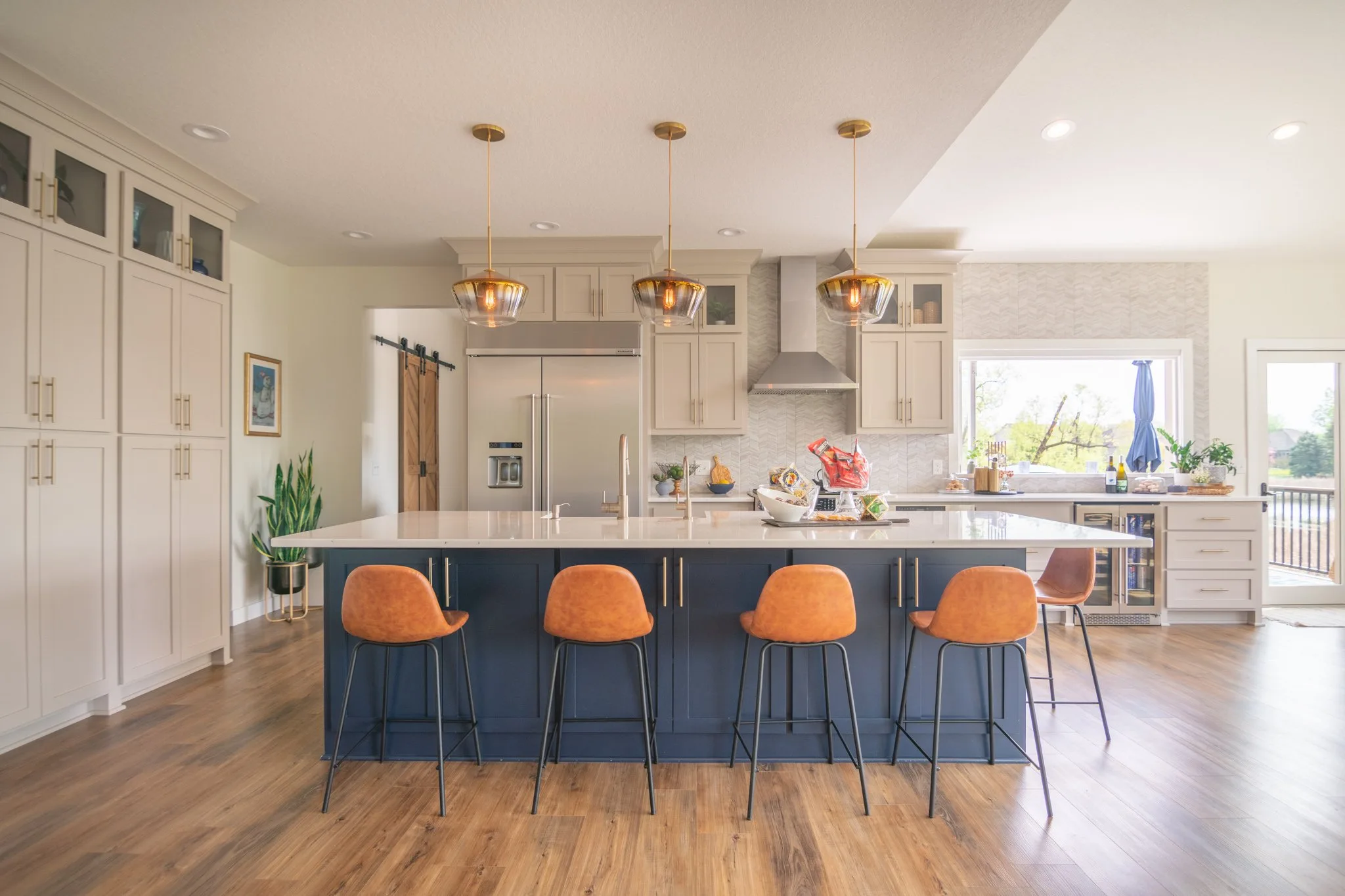 four leather back chairs with blue cabinets and large white quartz counter top in kitchen.