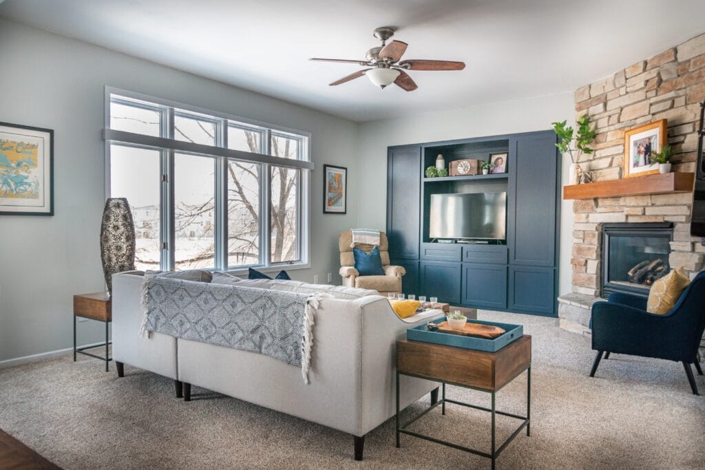 Living room with ceiling fan and blue wall with fireplace alongside.