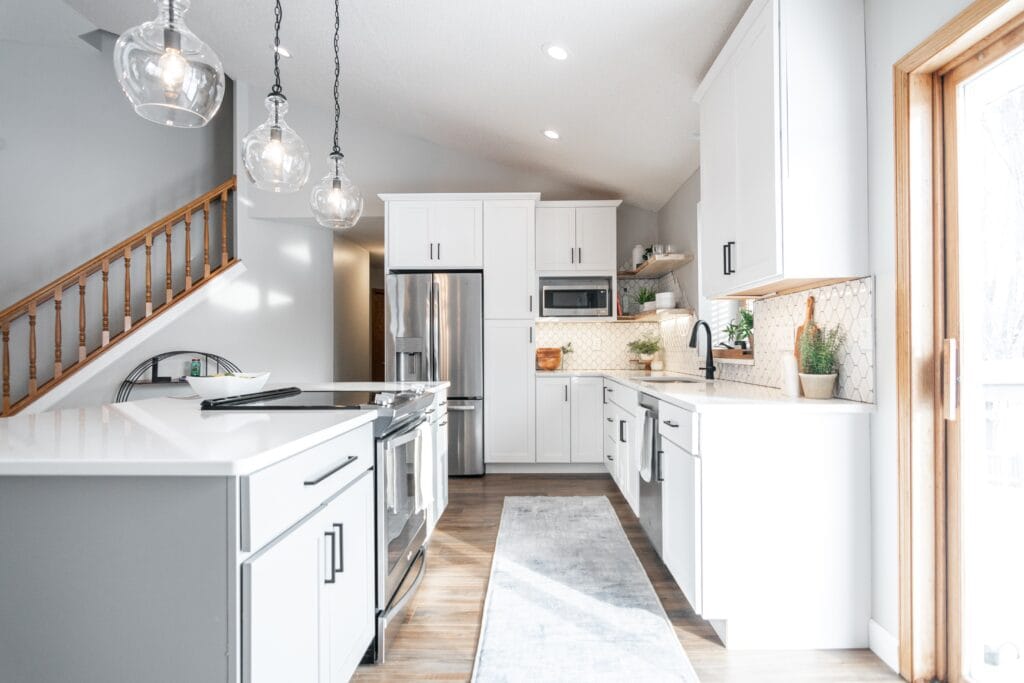In kitchen with white cabinets and large kitchen island with steps in the background.